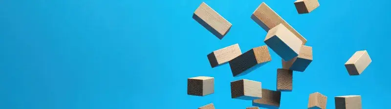 Динамичная композиция из деревянных кубиков, парящих на ярко-голубом фоне, символизирующая творчество, игривость и образовательные темы