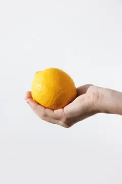 Человек держит лимон на белом фоне, есть место для текста