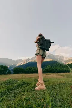 Активная женщина в походе на природе с рюкзаком и ботинками