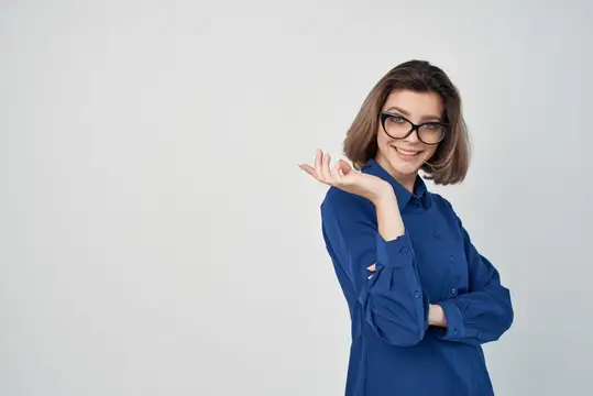 Улыбающаяся шатенка в очках и синей рубашке жестом показывает в сторону