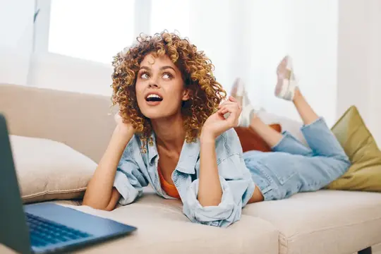 Улыбающаяся женщина печатает на ноутбуке в уютном домашнем офисе
