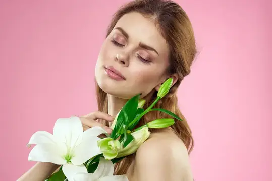 Молодая женщина с закрытыми глазами и белыми лилиями на розовом фоне