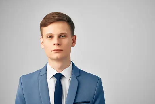 Молодой человек в синем костюме и галстуке на сером фоне
