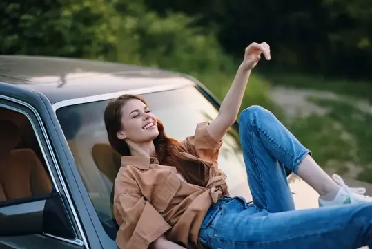 Молодая женщина с радостью выглядывает из окна автомобиля