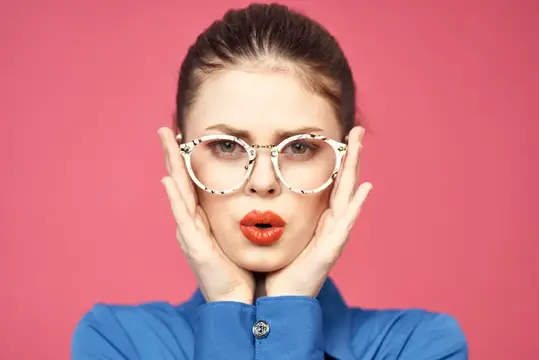 Молодая женщина в очках с красной помадой на розовом фоне