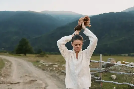 Женщина на отдыхе на природе в повседневной одежде на фоне живописного загородного пейзажа, улыбается на легком ветру, яркий свет, простая мода, умиротворенное настроение, естественные цвета