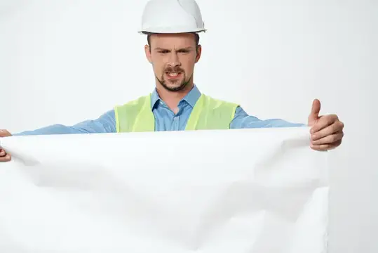 Строитель в белой каске с чертежами за работой
