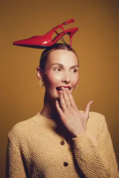 Удивлённая женщина с красной туфлей на голове
