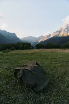 Рюкзак лежит на траве на фоне гор в долине