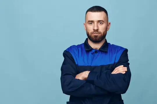 Молодой мужчина в синей рабочей форме со скрещёнными руками