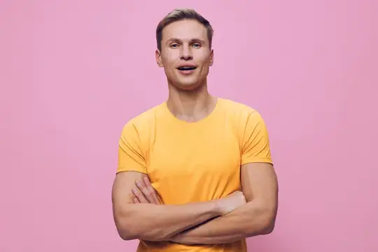 Улыбающийся парень в жёлтой футболке на розовом фоне