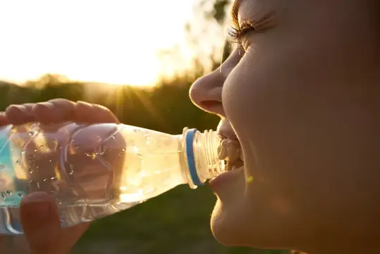 Девушка пьёт воду из бутылки на закате