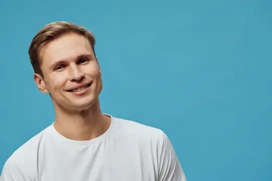 Улыбающийся светловолосый парень в белой футболке на голубом фоне