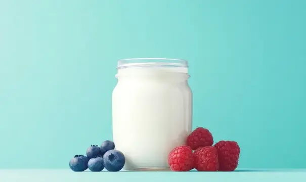 Стеклянная банка йогурта с малиной и голубикой на бирюзовом фоне