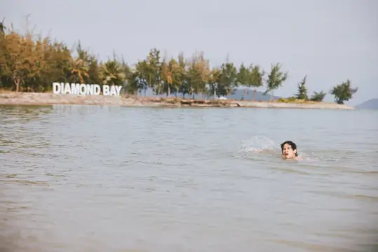 Мужчина плывёт в море у берега с надписью Diamond Bay
