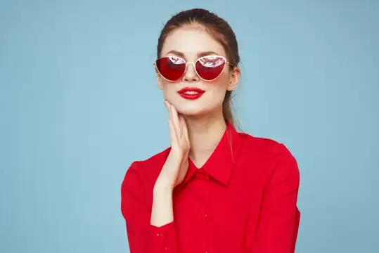 Красивая женщина в тёмных очках, красной рубашке, яркий макияж, эмоции, привлекательный взгляд, синий фон