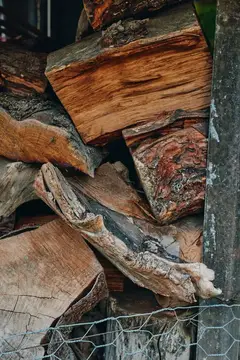 Крупный план поленницы из колотых дров, сложенных вручную, с детальной текстурой расколотой древесины твёрдых пород и выветренной коры