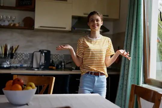 Улыбающаяся девушка в жёлтой футболке жестом приглашает на кухню