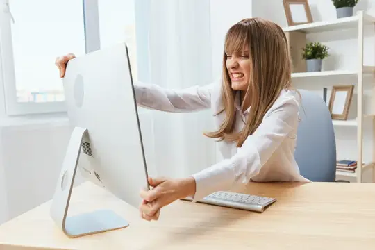 Женщина с трудом поворачивает монитор на офисном столе