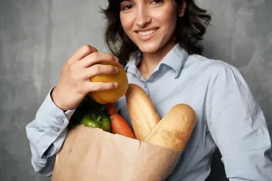 Улыбающаяся женщина с бумажным пакетом свежих продуктов
