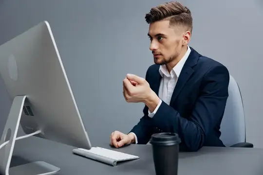Сосредоточенный мужчина в костюме работает за компьютером в офисе