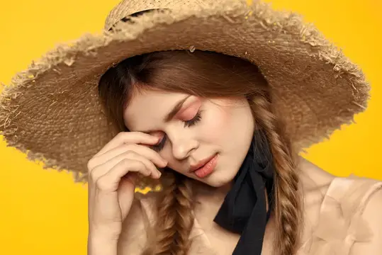 Молодая женщина в соломенной шляпе с косичками на жёлтом фоне