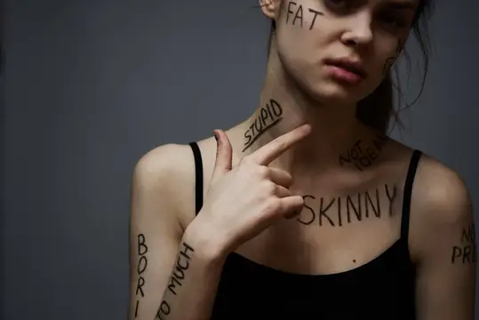Молодая девушка с надписями на теле указывает на слово Skinny