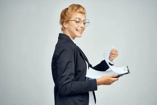 Женщина в деловом костюме, похожая на официальную бизнес-леди, держит документы в рабочей папке