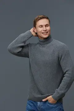 Улыбающийся мужчина в сером свитере на сером фоне