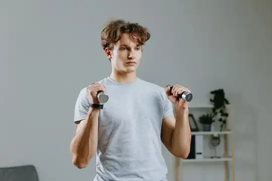 Мускулистый мужчина занимается спортом в серой комнате