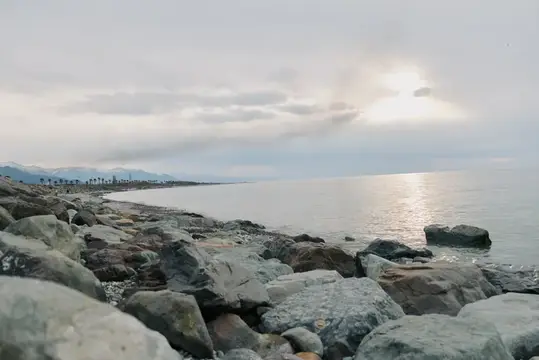 Каменистый берег моря под облачным небом с солнечным светом