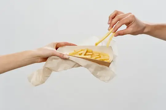 Руки достают картофель фри из бумажного пакета