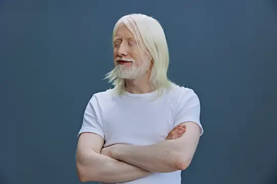 Пожилой мужчина со светлыми волосами и бородой стоит со скрещёнными руками