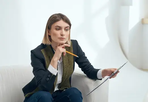 Задумчивая женщина с карандашом и планшетом в светлой гостиной