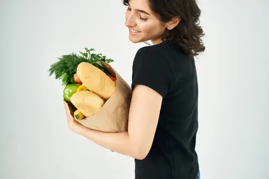 Женщина в черной футболке, бумажный пакет с продуктами крупным планом, здоровая еда