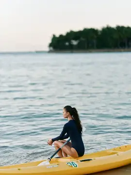 Девушка сидит на жёлтом каяке в спокойном море