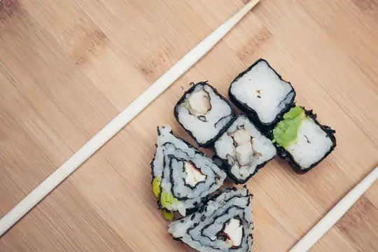 Роллы с начинкой и палочки на бамбуковой доске