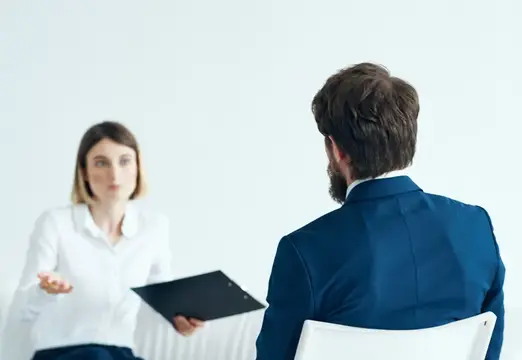 Женщина с папкой беседует с бородатым мужчиной в синем пиджаке