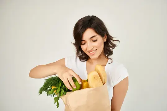 Весёлая брюнетка с пакетом продуктов, доставка из супермаркета