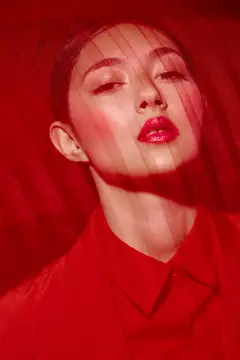 Крупный план женского лица с ярким макияжем и элегантной красной вуалью, одетой в монохромный ярко-красный наряд