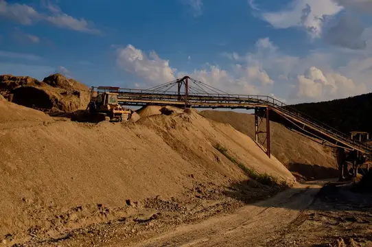 Песчаный карьер с транспортером и техникой под вечерним небом