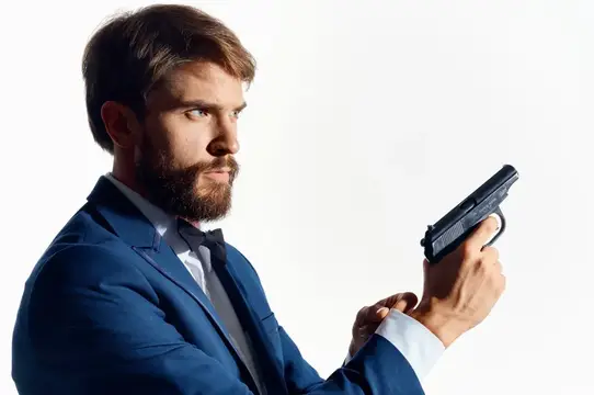 Бородатый мужчина в синем костюме целится из пистолета