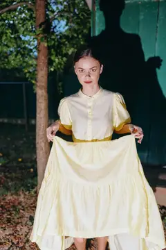 Женщина, платье, портрет, желтый, тень, винтаж, аутентичность, инклюзивность, стоит в саду, держа юбку, кинематографичное, мрачное, вечер
