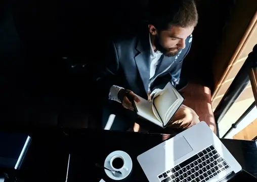 Бизнесмен сидит в кафе перед ноутбуком с чашкой кофе, работа, технологии, образ жизни