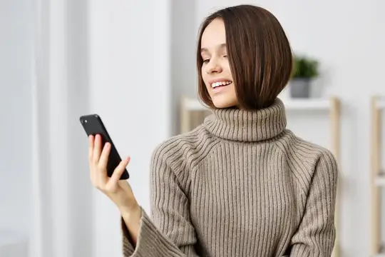 Красивая девушка-блогер сидит дома на диване, делает селфи на смартфон