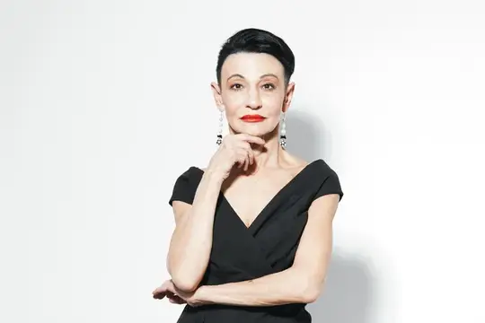 Элегантная женщина с короткой стрижкой в чёрном платье на белом фоне