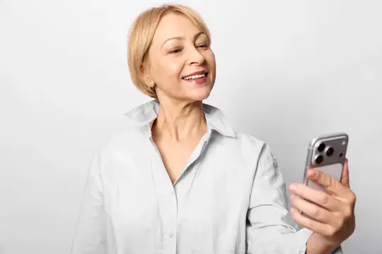 Пожилая женщина улыбается, держа смартфон