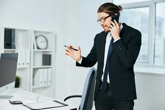 Мужчина в костюме говорит по телефону в офисе