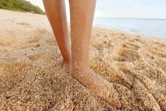 Ноги девушки в песке на пляже у моря