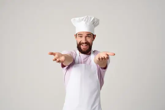 Эмоциональный мужчина-шеф-повар жестикулирует руками на кухне во время профессиональной работы